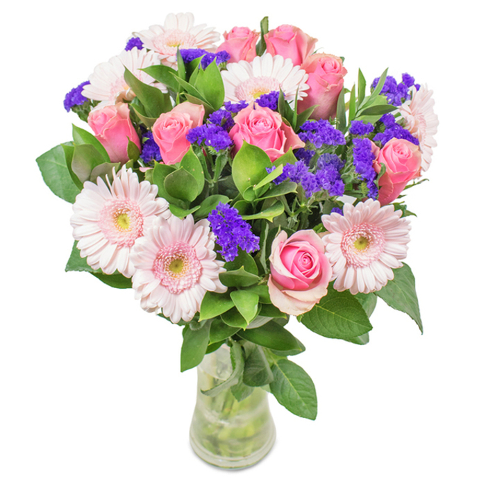Emanating elegance in every detail, this Chase Cross floral bouquet is presented in a slender, clear glass vase against a soft, neutral backdrop, capturing the timeless allure of freshly cut blooms. The display is anchored by approximately seven to nine classic pink roses, showing off meticulously unfurling petals in subtle spirals. Interspersed are five to seven pale pink gerbera daisies, their generous, radiating petals and nearly white centres adding a gentle cheer reminiscent of Chase Cross's own blossoming neighbourhood parks. Vivid purple statice flowers, clustered delicately among the pinks, introduce texture and depth, catching the eye like a patch of wildflowers along High Road. The foundation is made lush and vibrant with deep green, glossy foliage that breathes life into the entire arrangement and releases a subtle, woodland-fresh aroma. The transparent vase reveals the crisp green stems and sparkling water within, underscoring freshness and the personal touch of a local florist. This arrangement is ideal for birthdays, anniversaries, or as a stylish centrepiece, capturing moments of celebration and affection for Chase Cross homes or offices-a floral expression filled with joy, thoughtfulness, and local charm.